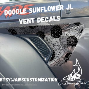 May include: A black and white sunflower decal for a Jeep JL vent. The decal features a repeating pattern of sunflowers with black centers and white petals. The decal is labeled "Doodle Sunflower JL Vent Decals" and "JAWS Customization".