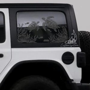 May include: A white Jeep Wrangler with a black shark fin antenna and a custom window decal featuring two sea turtles swimming in a coral reef. The decal also includes the text "JAWS Customization".