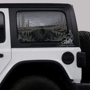 May include: A white vehicle with a dark-tinted rear side window featuring a black decal of a landscape. The design includes pine trees, mountains, a lake, and a sun with a heart-shaped center. The text JAWS Customization is printed in white.