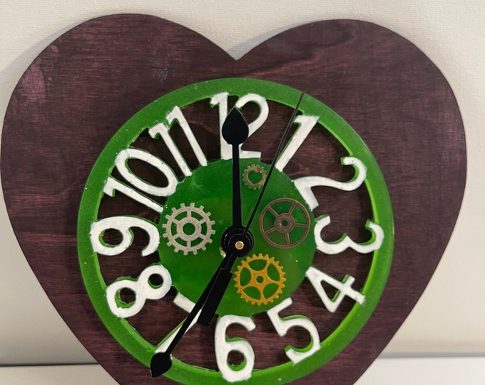 Green acrylic clock with white numbers and metallic gears on a wooden black cherry  Heart background