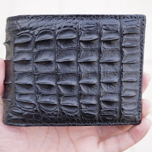 May include: A black alligator skin wallet with a textured pattern.