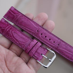 Pode incluir: Duas pulseiras de relógio de jacaré rosa com uma fivela prateada. As pulseiras são feitas de couro de jacaré genuíno e têm um padrão texturizado.