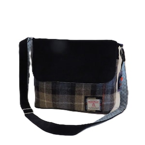 May include: A rectangular messenger bag with a black flap and strap. The main body features a plaid pattern in shades of gray, brown, and blue. A small label is sewn on the front. The bag has a blue and white patterned side.