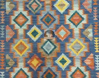 May include: A blue rug with a geometric pattern of orange, yellow, and green diamonds. The rug is hand-woven and has a traditional design.