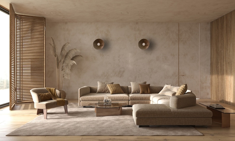 May include: A light brown sectional sofa with multiple pillows in a living room with a light brown rug, a wooden coffee table, and two round wall sconces.