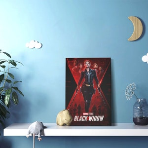 Puede incluir: Un p&oacute;ster de pel&iacute;cula para la pel&iacute;cula de Marvel Studios "Black Widow" con un fondo rojo y negro con una mujer con un traje negro sosteniendo dos armas. La mujer est&aacute; de pie frente a un grupo de otras personas.