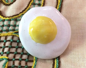 Flat egg brooch in earthenware