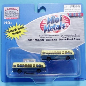 May include: A blue and cream 1:160 scale model of a GMC TDH-3610 Transit Bus. The model is packaged in a blue and red box with the words "Mini Metals" on the front. The box also includes the words "Waterslide Decals Included!" and "Adult Collectible".