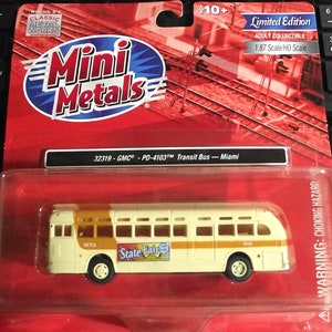 Peut inclure: Un modèle de bus crème avec une bande brune et une publicité "State Fair". Le bus est étiqueté "MTA" et "948". Le bus fait partie d'une collection "Mini Metals", un objet de collection pour adultes en édition limitée.