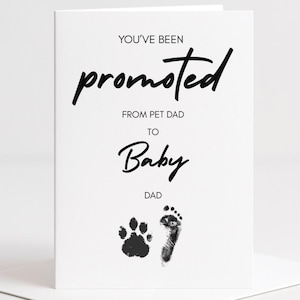 Peut inclure: Carte de félicitations blanche avec texte noir : "Vous avez été promu de papa de chien à papa de bébé." Une empreinte de patte et un pied de bébé sont imprimés en dessous. La carte est sur une enveloppe blanche.
