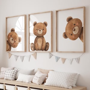 Peut inclure: Trois impressions encadrées présentant des illustrations à l'aquarelle d'ours en peluche bruns. Les ours ont des joues roses et sont dans différentes poses. Les cadres sont brun clair, et les impressions sont affichées au-dessus d'un banc avec des coussins et une bannière.