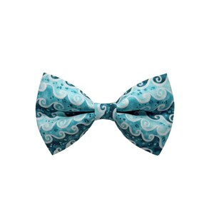 May include: A turquoise bow tie with a repeating wave pattern in white and darker teal. The bow tie is a classic shape, with a knot in the center and flared ends. The fabric has a slight sheen.