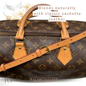 May include: Brown monogram handbag with tan leather details and a detachable shoulder strap. The strap has a gold-coloured buckle. The image text says "Blends naturally with classic vachetta leather" and "Bag not included."