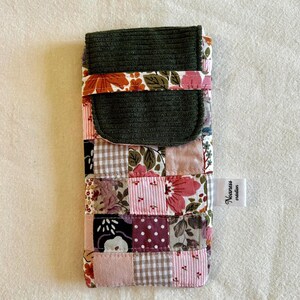 Könnte beinhalten: Eine rechteckige Stofftasche mit einem Patchwork-Design aus Blumen-, Vichy- und Punktemustern in Rosa-, Braun- und Weißtönen. Sie hat eine dunkelgrüne Kord-Klappe und ein weißes Etikett an der Seite mit dem aufgedruckten Text Noaness création.