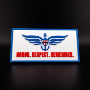 May include: A rectangular patch with a white background, blue border, and a blue and red emblem. The emblem features a stylized anchor, wings, and a shield. The words "HONOR. RESPECT. REMEMBER." are in red.