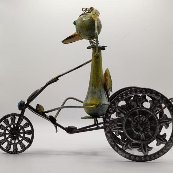 Grande figurine en métal représentant un canard faisant du tricycle