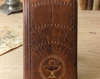 Small antique brown leather vesperal missal with a Holy Grail motif engraved on the cover. Signed 1945.