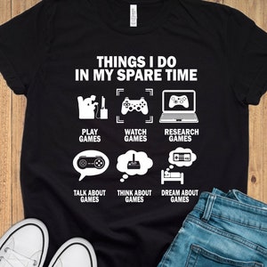 May include: Black t-shirt with white text that reads "Things I do in my spare time". The text is surrounded by icons of video game controllers, a computer, and a bed.