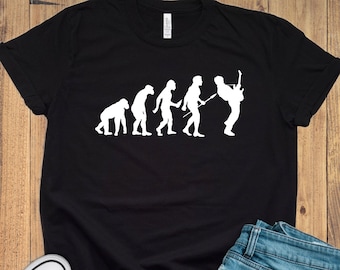 May include: Black t-shirt featuring a white graphic of the evolution of man, culminating in a person playing a guitar.
