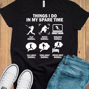 Op de afbeelding: Een zwart T-shirt met witte tekst die "Things I do in my spare time" luidt. De tekst wordt omringd door illustraties van een persoon die honkbal speelt, honkbal kijkt, honkbal onderzoekt, over honkbal praat, aan honkbal denkt en van honkbal droomt.