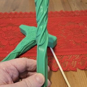 May include: A green plastic wand with a swirling pattern. The wand is about 12 inches long and has a flat, rectangular end.