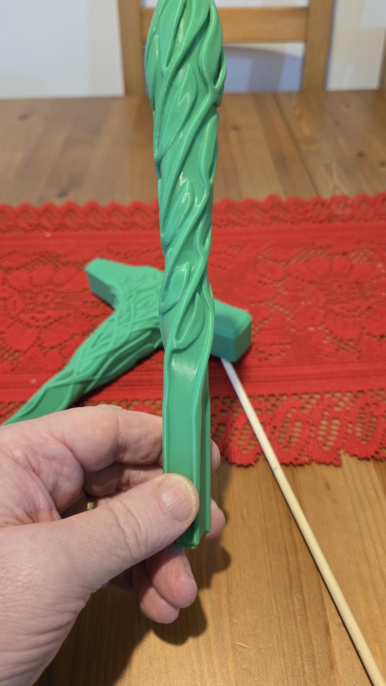 May include: A green plastic wand with a swirling pattern. The wand is about 12 inches long and has a flat, rectangular end.
