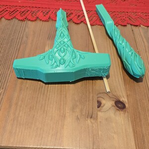 May include: A green plastic hammer with a detailed design, a wooden stick, and a green plastic handle with a similar design.