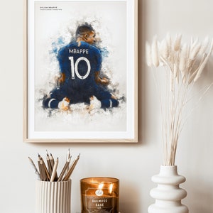 May include: A framed watercolor painting of a soccer player wearing a blue jersey with the number 10 and the name "MBAPPE" on the back. The player is kneeling on a field with a blurred background.