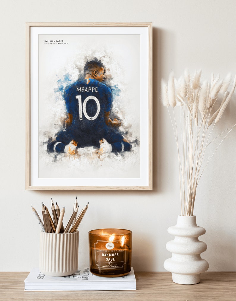 May include: A framed watercolor painting of a soccer player wearing a blue jersey with the number 10 and the name "MBAPPE" on the back. The player is kneeling on a field with a blurred background.