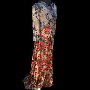 May include: A long, flowing dress with a floral pattern. The dress features a bodice with a blue and white watercolor design and a skirt with large red and pink flowers on a cream background. The dress has long sleeves and a ruffled collar.