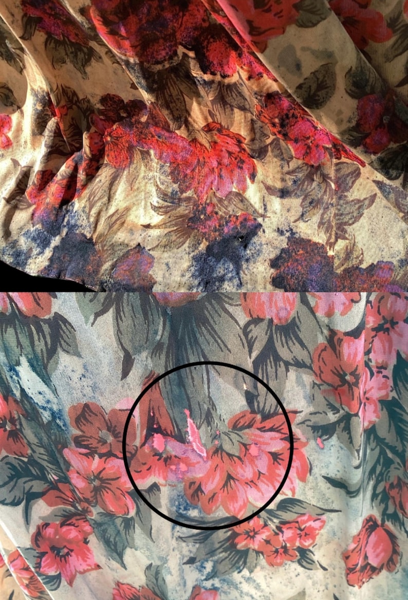 May include: Close-up of a fabric with a floral pattern. The design features large, stylized flowers in shades of red, pink, and purple against a beige background. The fabric has a slightly wrinkled texture, suggesting it may be a lightweight material.