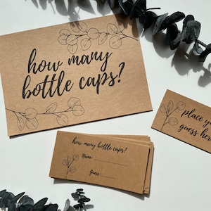 May include: Kraft paper game cards with the text "how many bottle caps?" and "place your guess here". The cards have a botanical illustration and are accompanied by eucalyptus branches.