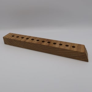 Può includere: Un porta matite in legno con 12 fori per matite. Il porta matite è in legno marrone chiaro con una venatura naturale.