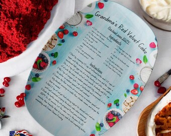 May include: A blue and white oval ceramic serving tray with a red velvet cake recipe printed on it. The recipe includes ingredients and instructions for baking a red velvet cake. The tray is decorated with images of red and blue berries, cherries, and white chocolate.