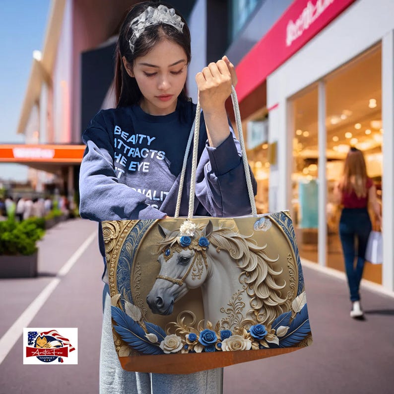 Stylish oversized beach bag with rope handles and horse artwork against a gold and blue background, trendy travel essentials.
Elegant oversized tote with cream rope handles and detailed horse design, a luxurious addition to any travel collection.