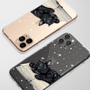 May include: Two phone cases with a black cat sleeping on a book design. One case is gold with white stars, the other is dark gray with white stars. The cat illustration is black and white.