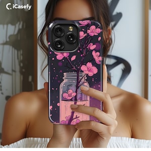 Könnte beinhalten: Eine schwarze Handyhülle mit einem Blumenmuster. Das Design zeigt rosa Blumen in einem Glasgefäß vor einem dunkelblauen Hintergrund. Die Hülle hat ein klares Kameraobjektiv.