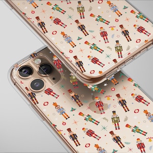 Puede incluir: Dos fundas transparentes para teléfono con un patrón repetido de coloridos soldados cascanueces y acentos festivos. Las fundas están hechas de un material transparente.