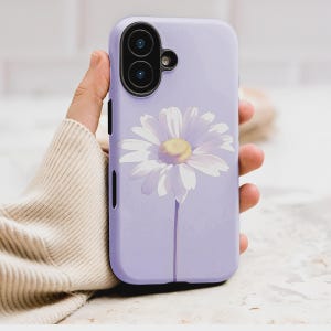 May include: A lilac phone case decorated with a white daisy and a yellow centre. The floral design is centrally placed, with the flower's stem extending downwards. The case has a camera cutout and side buttons.