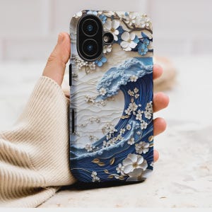 May include: A phone case featuring a 3D design of a blue ocean wave with white floral accents. The case has a glossy finish and a camera cutout. The design includes gold leaf details and a white and blue color scheme.