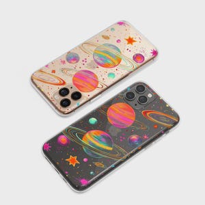 May include: Two phone cases with a colorful space-themed design. The cases feature planets with rings, stars, and other celestial elements in vibrant colors. One case has a clear background, and the other has a dark background.