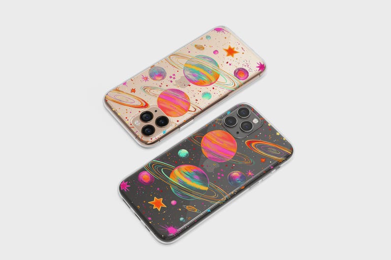 May include: Two phone cases with a colorful space-themed design. The cases feature planets with rings, stars, and other celestial elements in vibrant colors. One case has a clear background, and the other has a dark background.