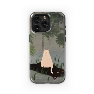 May include: A phone case with a white cat sitting on a black cat in a green and gray forest scene.