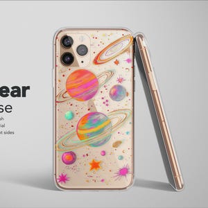 May include: Clear phone case with a colorful planet design. The case features planets with rings, stars, and colorful splashes. The phone case is made of soft material with transparent sides. The text "Clear Case" is displayed.