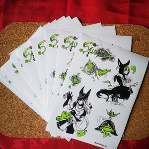May include: A stack of white stickers with black and green illustrations of a character with a wolf head and a plant. The text "Summer" is written in green on the stickers. The stickers are on a cork surface.