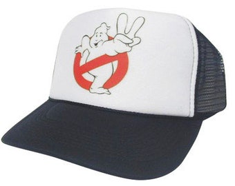 Op de afbeelding: Een witte en zwarte trucker-pet met een rood 'geen geest'-symbool en een cartoon-geest met een vredesteken.