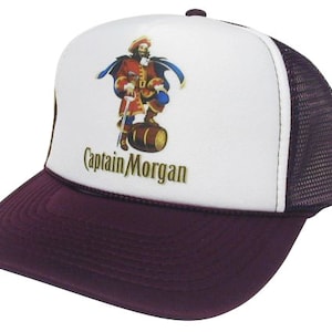 Könnte beinhalten: Eine weiße und burgunderfarbene Trucker-Kappe mit Netzrücken. Die Vorderseite der Kappe zeigt ein Cartoon-Bild eines Piraten, der ein Rumfass hält. Der Text "Captain Morgan" ist unter dem Bild aufgedruckt.