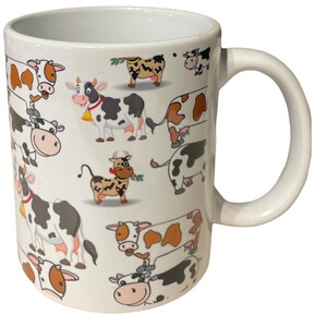 May include: White ceramic mug with a pattern of cartoon cows in black, white, brown, and orange. The cows are in various poses, some with bells around their necks.