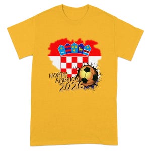Yellow t-shirt with a cracked soccer ball and "North America 2026" text.