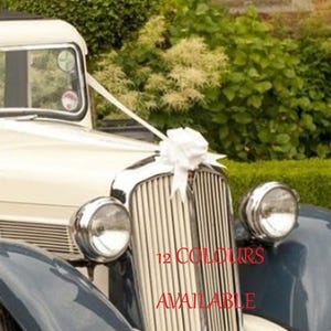 May include: A cream-coloured vintage car with chrome detailing, a white bow, and a ribbon. The car features a dark blue fender and a classic grill. The text "12 COLOURS AVAILABLE" is visible.